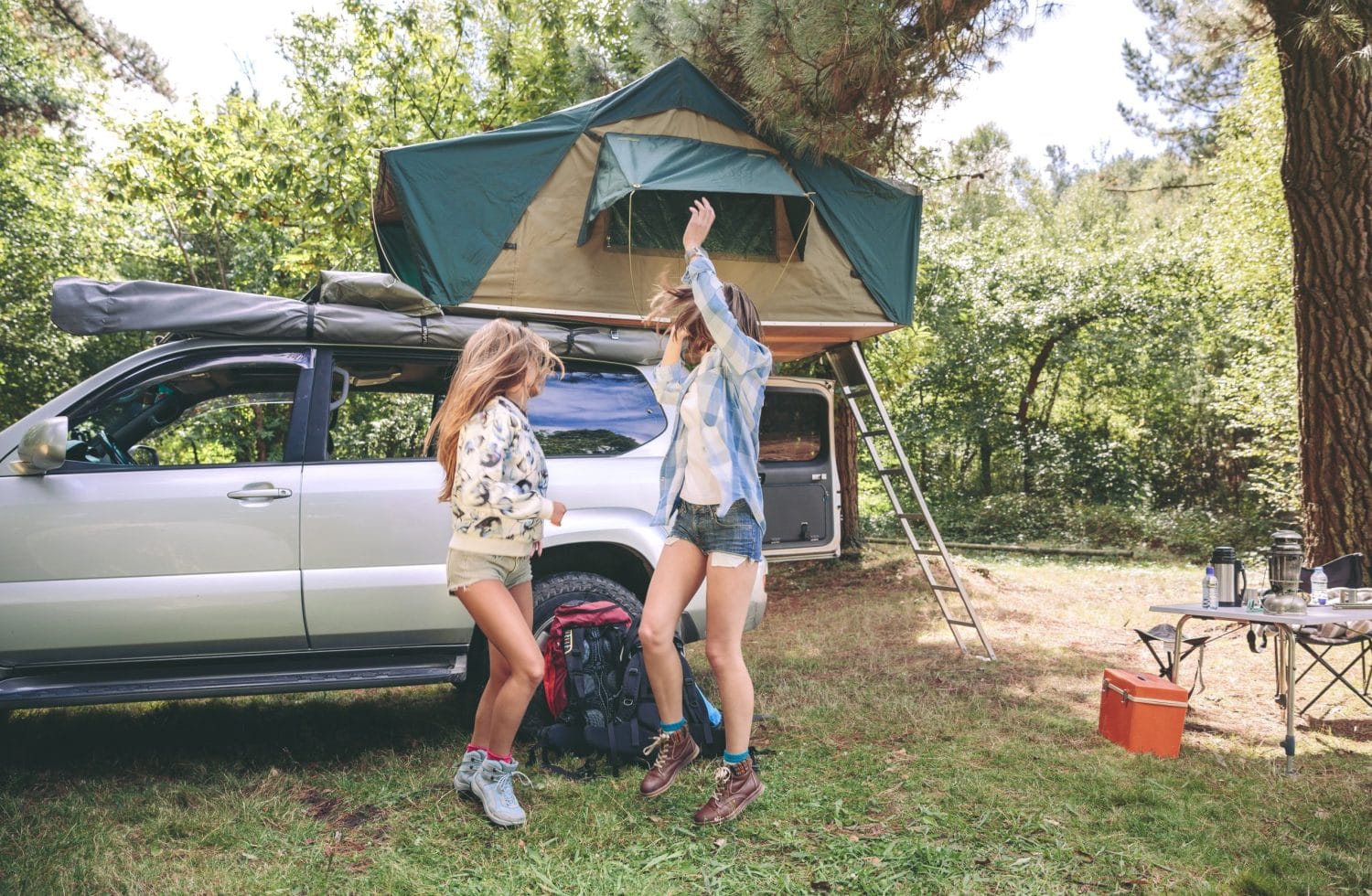 Young women friends having fun in a campsite into the forest. Leisure time and enjoyment concept.